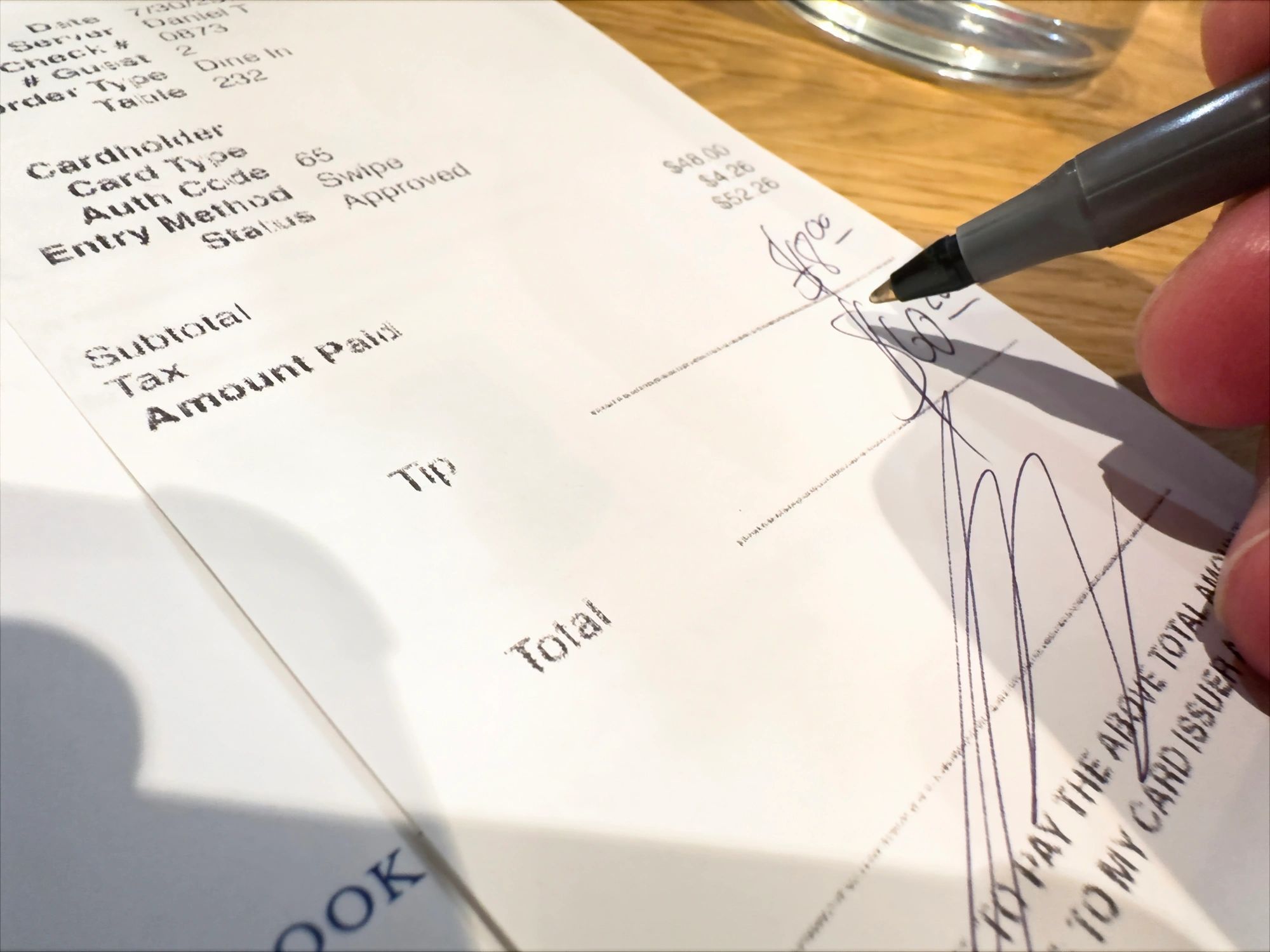 Person signing a bill or document at a table