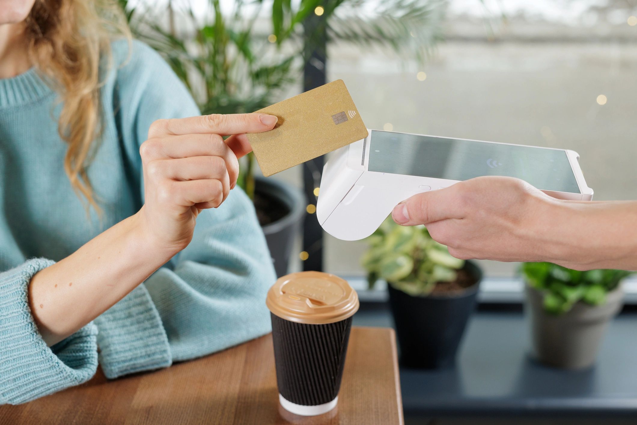 Contactless card payment on a handheld reader at a cafe table